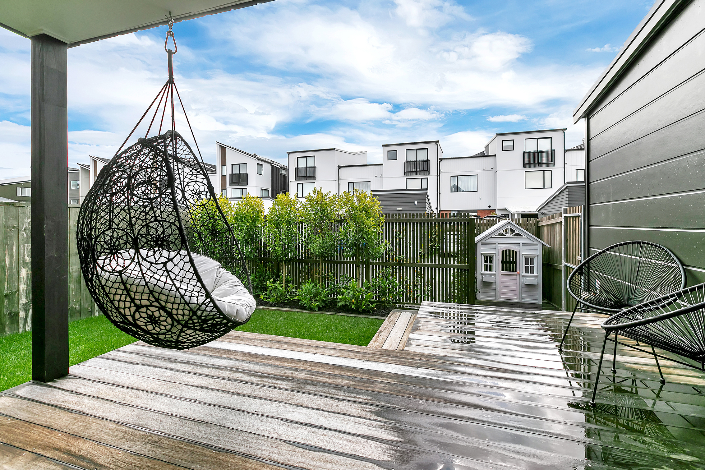Covered outdoor deck with hanging chair and family friendly backyard Hobsonville Jev Matt.jpg